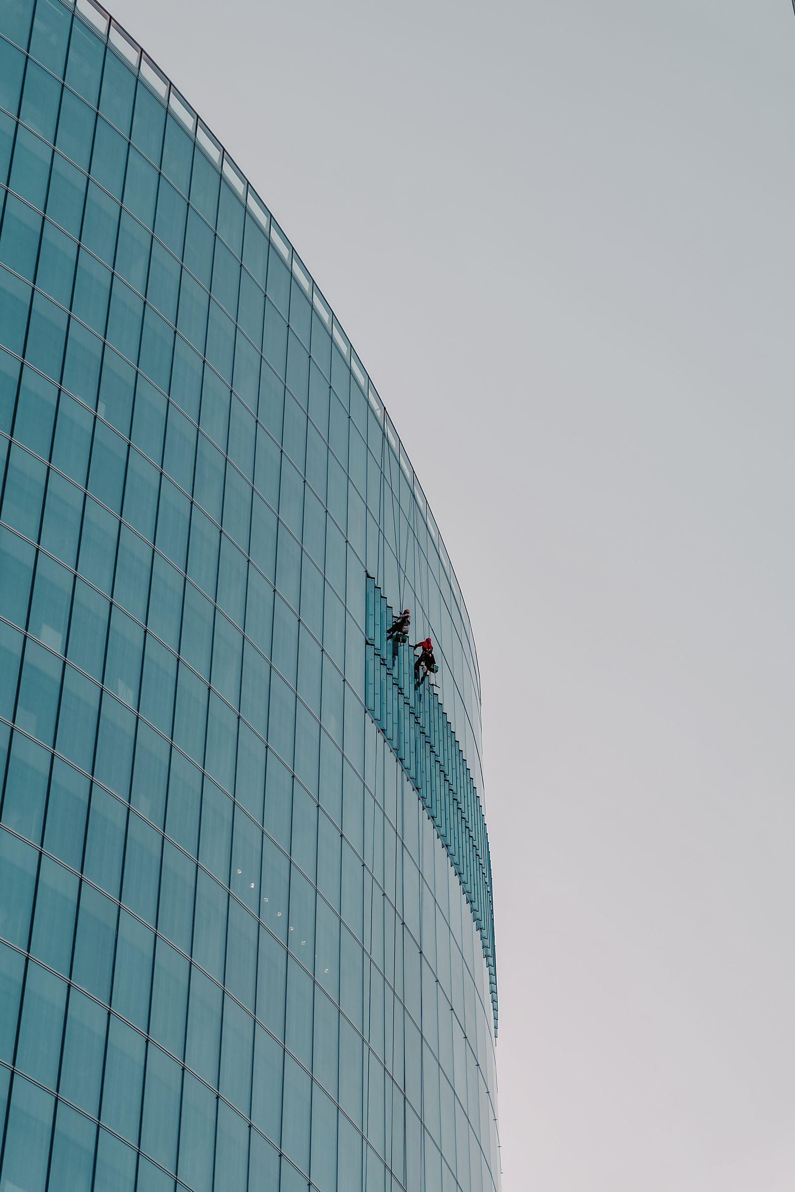 Agents de nettoyage suspendus sur une façade vitrée